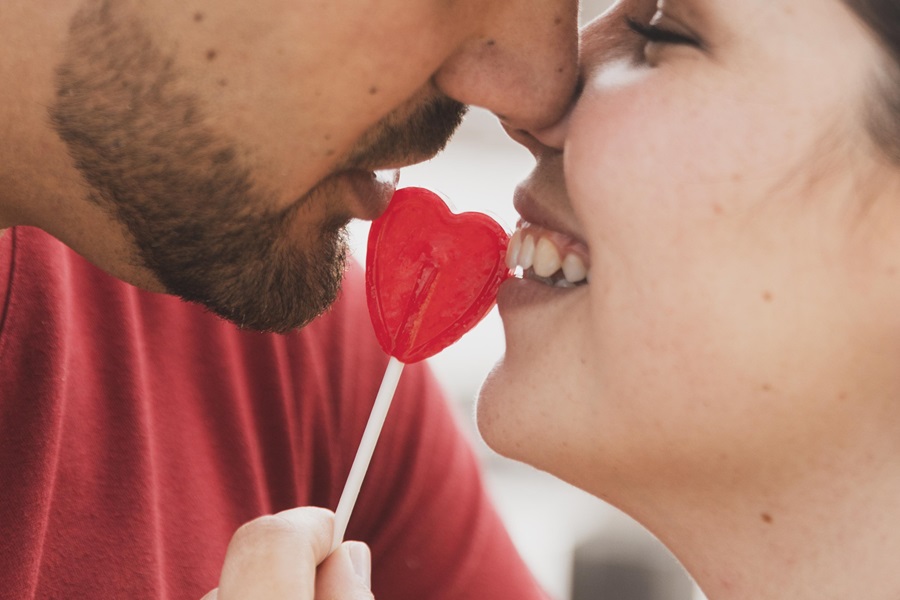 coppia che si bacia e tra loro un lecca lecca a forma di cuore relazione sessualità